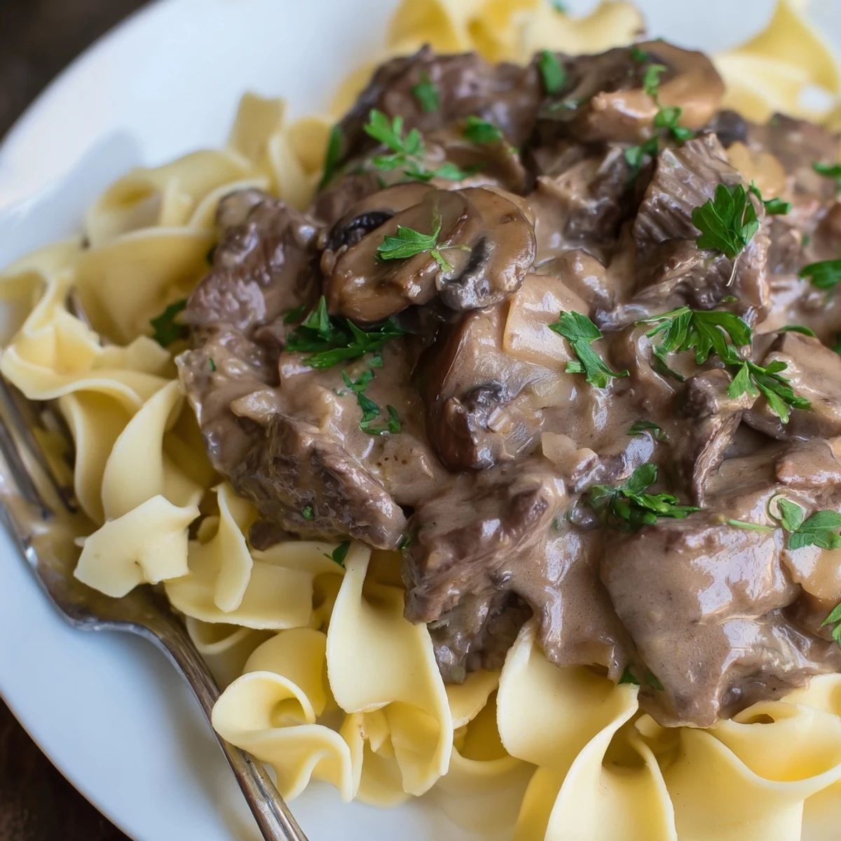 Classic Beef Stroganoff served over silky egg noodles garnished with fresh parsley.  