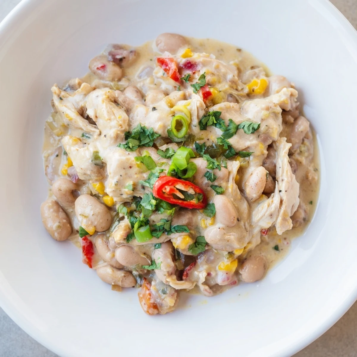A steaming bowl of Creamy White Chicken Chili with beans, garnished and ready to be served.