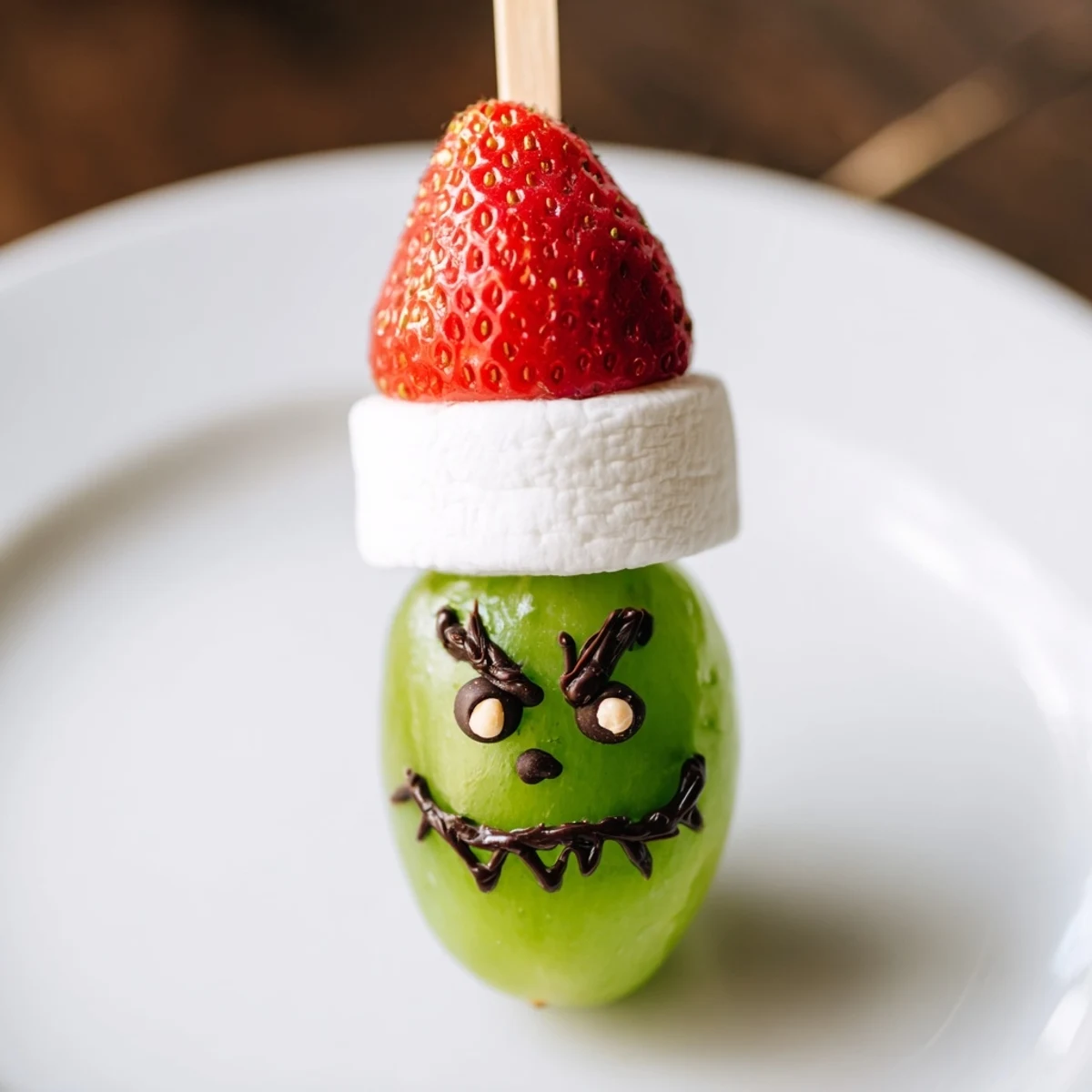 Grinch Snack faces: a cheerful close-up of green grapes, marshmallows, and strawberry "hats."