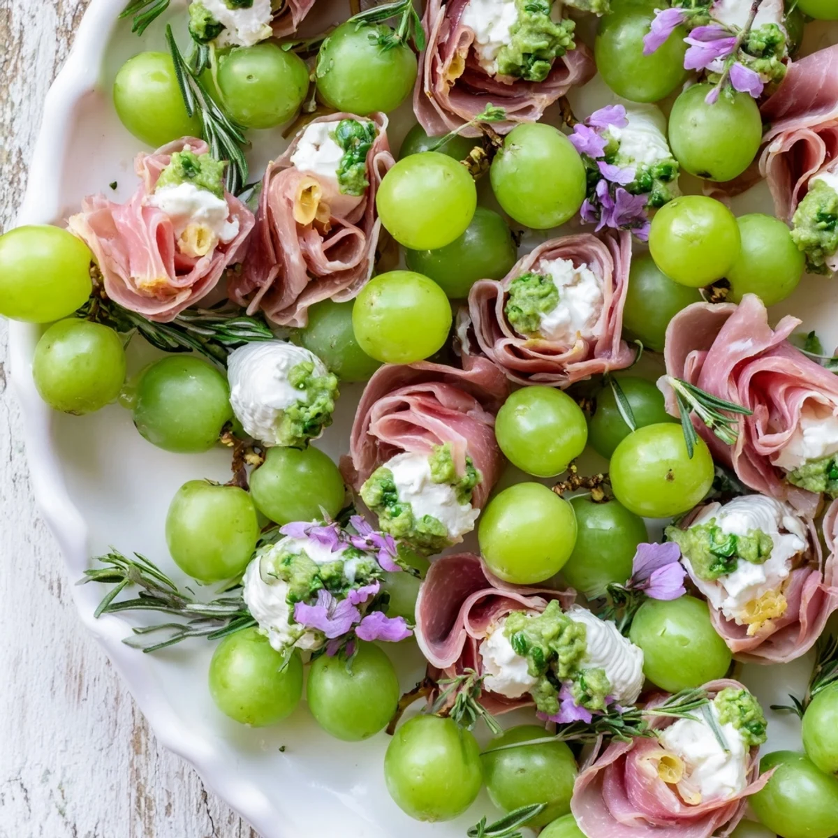 This stunning Mistletoe Kissing Ball combines fresh herbs, cheese balls, and grapes to create a delicious and visually appealing appetizer.