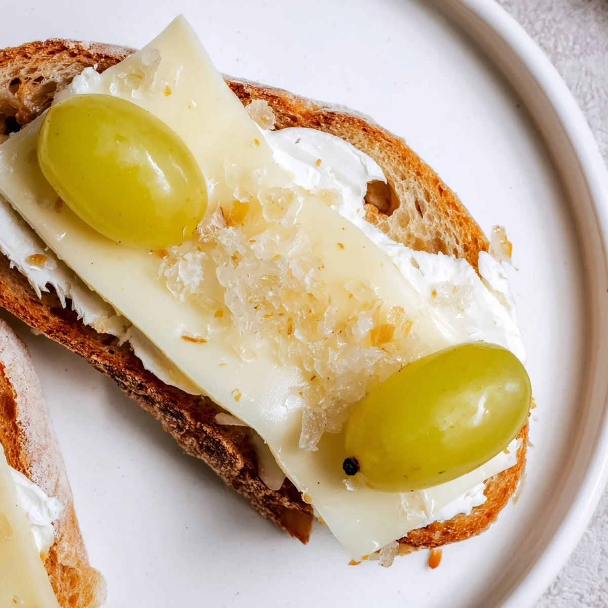 Up-close shot of individual Sparkling Champagne Toasts, featuring creamy cheese, sparkling grapes, and gold dust.