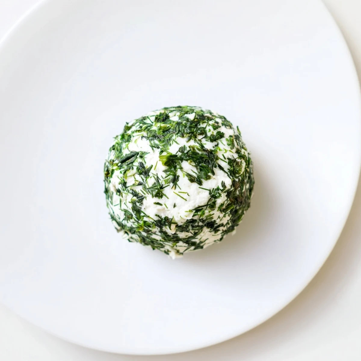 Close-up of The Mossy Stone appetizer, showing creamy goat cheese covered in fresh herbs.