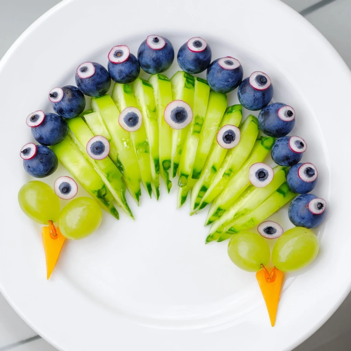 A delicious and refreshing Peacock Tail platter, showcasing colorful grapes and cucumber with radish eyes.