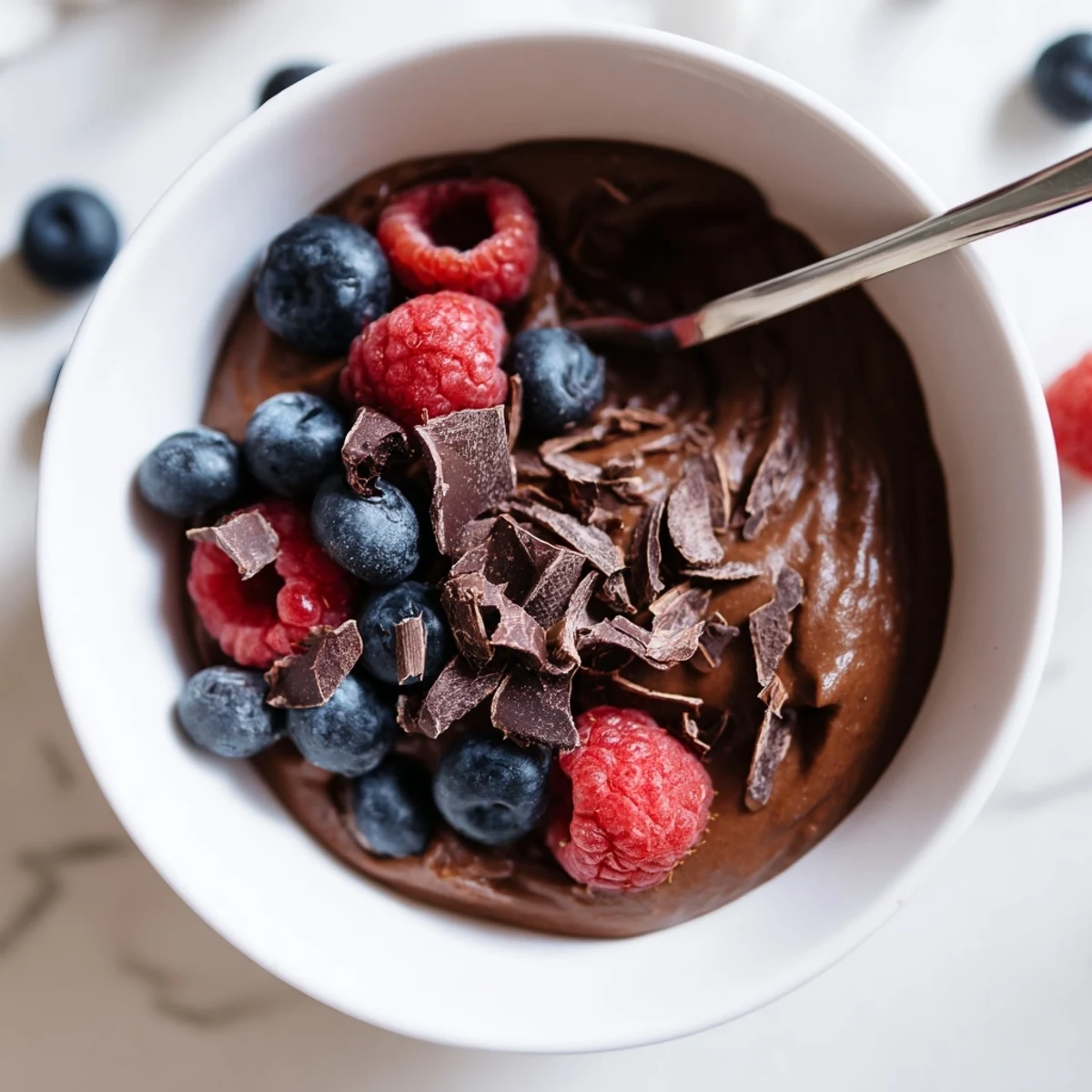 Creamy Avocado Chocolate Pudding, a vegan delight, is pictured alongside shaved dark chocolate.