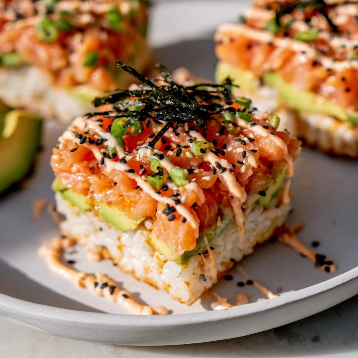 Golden, crispy rice salmon stacks with creamy avocado and spicy mayo, perfect appetizer.