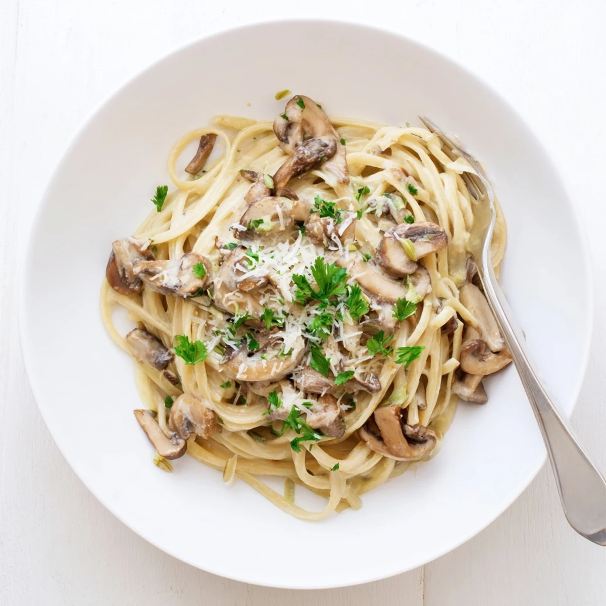 Creamy Mushroom Linguine pasta twirled on a fork, showcasing sautéed mushrooms in a silky cream sauce with fresh parsley garnish.  