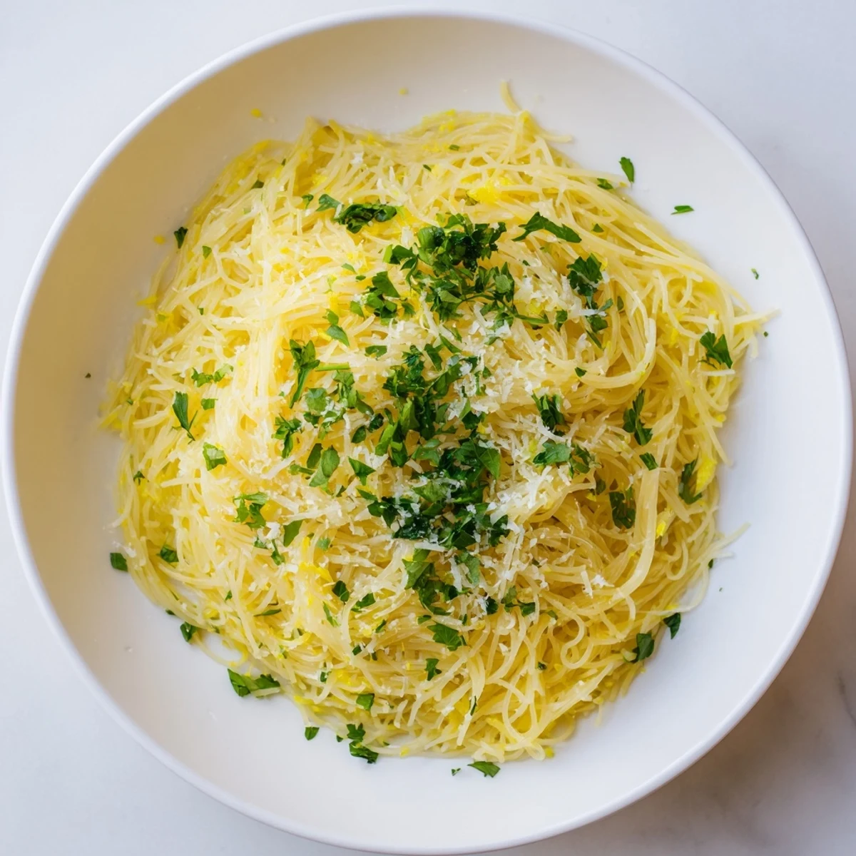 A close-up of Lemon Butter Pasta Light with capellini coated in silky sauce, fresh parsley, and grated Parmesan.  