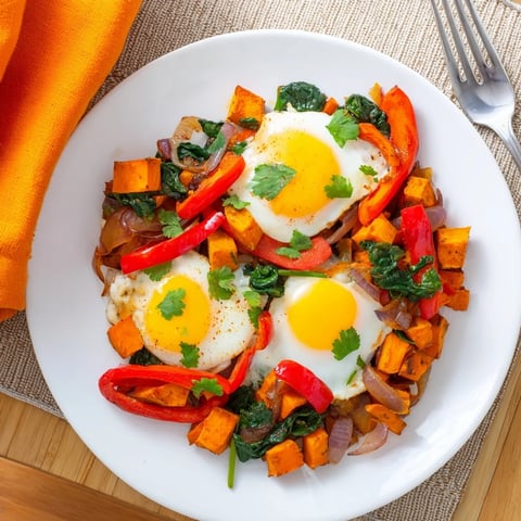 Hearty sweet potato hash with eggs topped with vibrant fresh herbs and spices.  