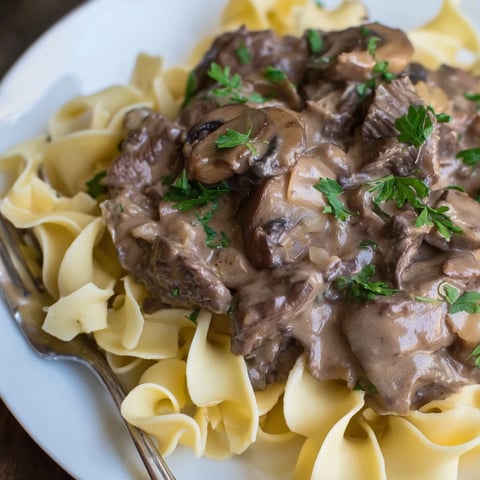 Classic Beef Stroganoff served over silky egg noodles garnished with fresh parsley.  