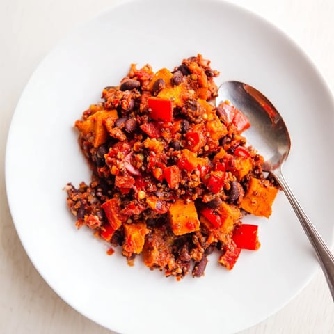 Steaming bowl of Sweet Potato & Black Bean Chili, garnished with cilantro, ready to eat.