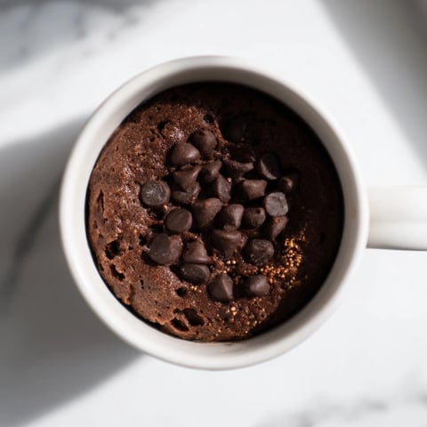 Fluffy microwaved mug cake, warm and chocolatey, is perfect for a quick dessert.