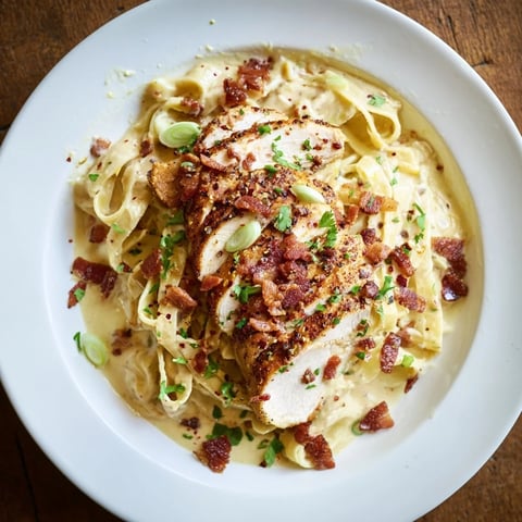 Southern Style Creamy Parmesan Chicken Pasta, a comforting plate of pasta topped with sliced, golden-brown chicken.