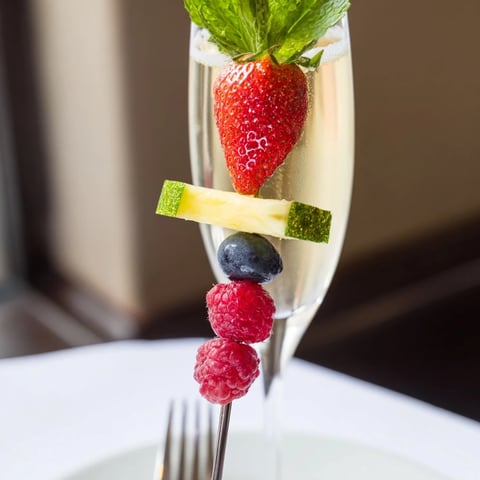 Colorful arrangement of Champagne Flute Fruit Garnishes featuring strawberries and pineapple, festive for New Year's.
