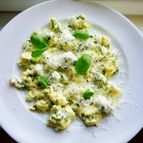 Fluffy Pesto Cottage Cheese Eggs, a vibrant breakfast, garnished with fresh basil and Parmesan cheese.