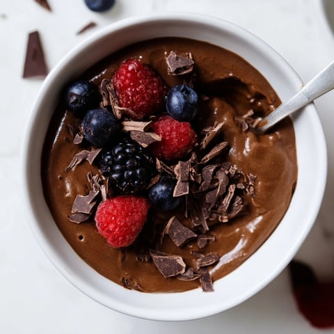 Smooth, dark Avocado Chocolate Pudding, garnished with fresh berries ready to be enjoyed.