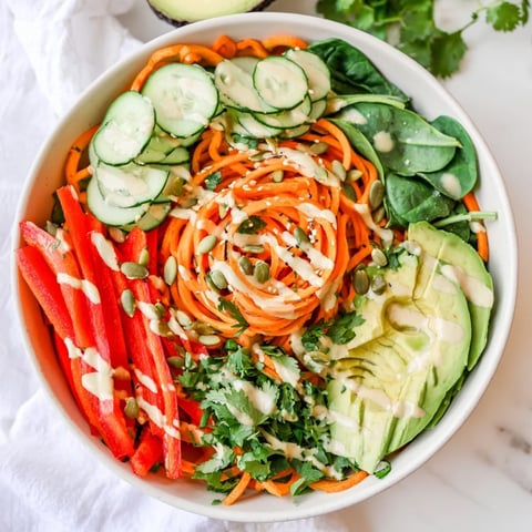 A vibrant Carrot Noodle Skincare Bowl topped with creamy avocado and fresh spinach.