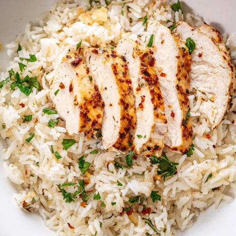 Fluffy Garlic Butter Rice with Chicken features tender grilled chicken breast resting on a bed of savory, buttery rice.  