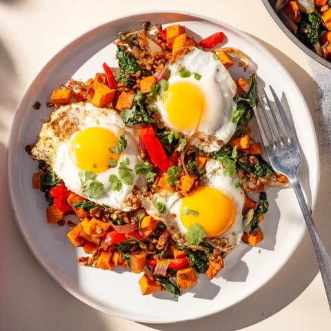 Colorful sweet potato hash with perfectly cooked eggs and sautéed vegetables.  