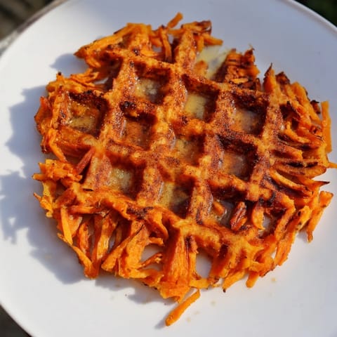 A stack of freshly made sweet potato waffles, drizzled with sweet maple syrup, perfect for weekend brunch.