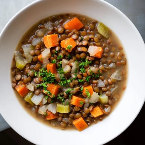 Rustic close-up of hearty Lentil Soup, a comforting mix of carrots and celery in rich broth.