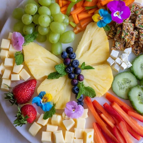 Delightful Butterfly Summer Board with vibrant fruit butterflies, cheeses, and edible flowers arranged artfully.