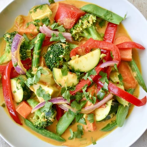 A steaming bowl of flavorful Coconut Curry Vegetables, perfect with fresh cilantro and lime wedges.