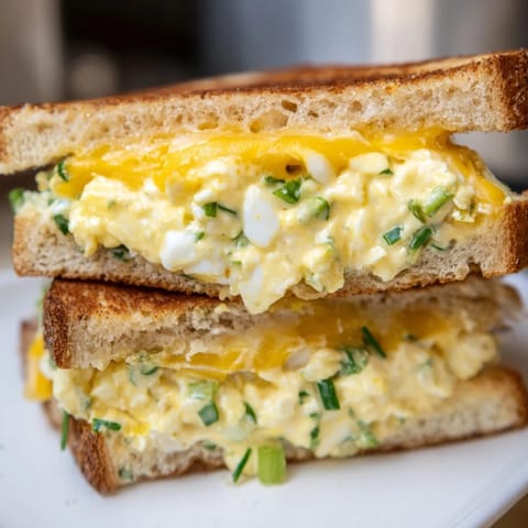 A close-up shot of the savory Egg Salad Grilled Cheese with visible creamy filling and golden crust.