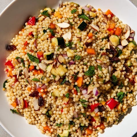 A colorful bowl of Moroccan couscous salad with perfectly roasted vegetables and bright herbs.