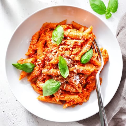 Steam rises from a bowl of sun-dried tomato pesto pasta served alongside a crisp salad.  