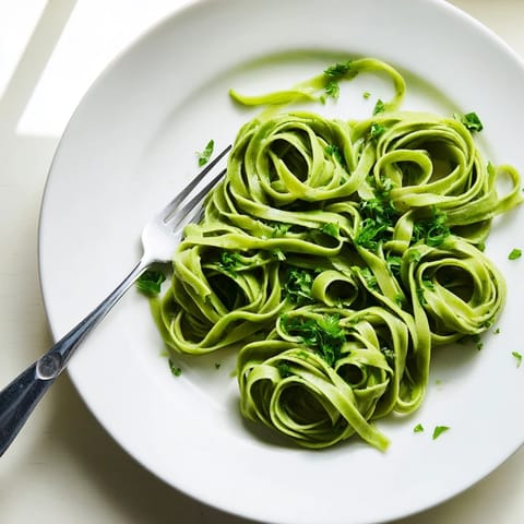 Homemade spinach pasta dough being kneaded, showing its elastic texture and bright color for Italian dishes.  