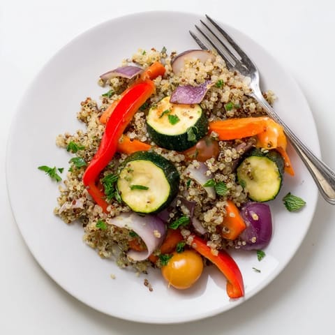 Colorful quinoa vegetable pilaf with roasted bell peppers and zucchini, topped with parsley and mint for a fresh finish.