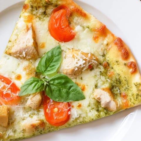 Savory thin-crust pizza topped with tender chicken, fragrant basil pesto, juicy tomatoes, and creamy mozzarella, perfect for a quick weeknight dinner.  