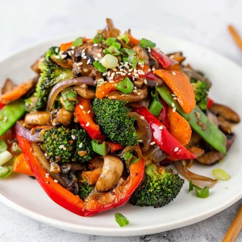 A close-up of fresh Ginger Stir-Fried Vegetables topped with toasted sesame seeds and green onions, served steaming over a bed of fluffy jasmine rice.  