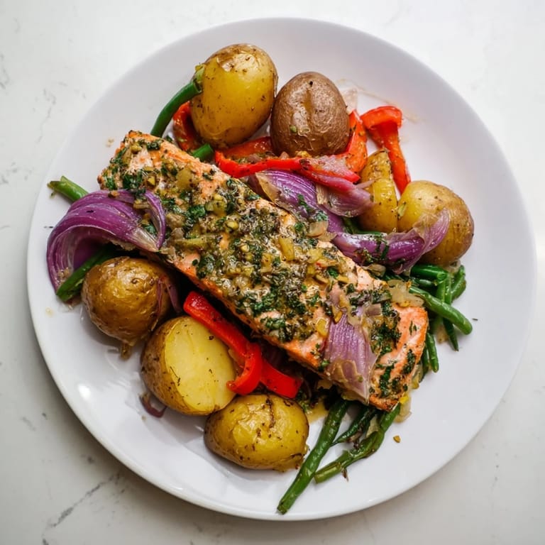 Enjoy a close-up of flaky Lemon Herb Salmon & Potato alongside roasted vegetables, bursting with flavor.