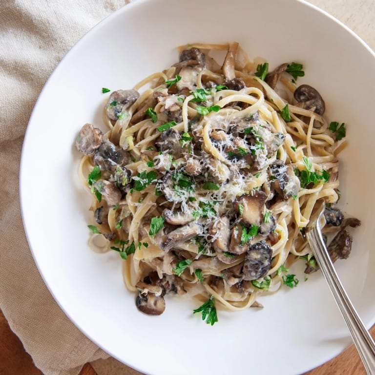 Steaming Creamy Mushroom Linguine on a rustic table, featuring tender mushrooms and melted Parmesan cheese, perfect for a cozy vegetarian dinner.