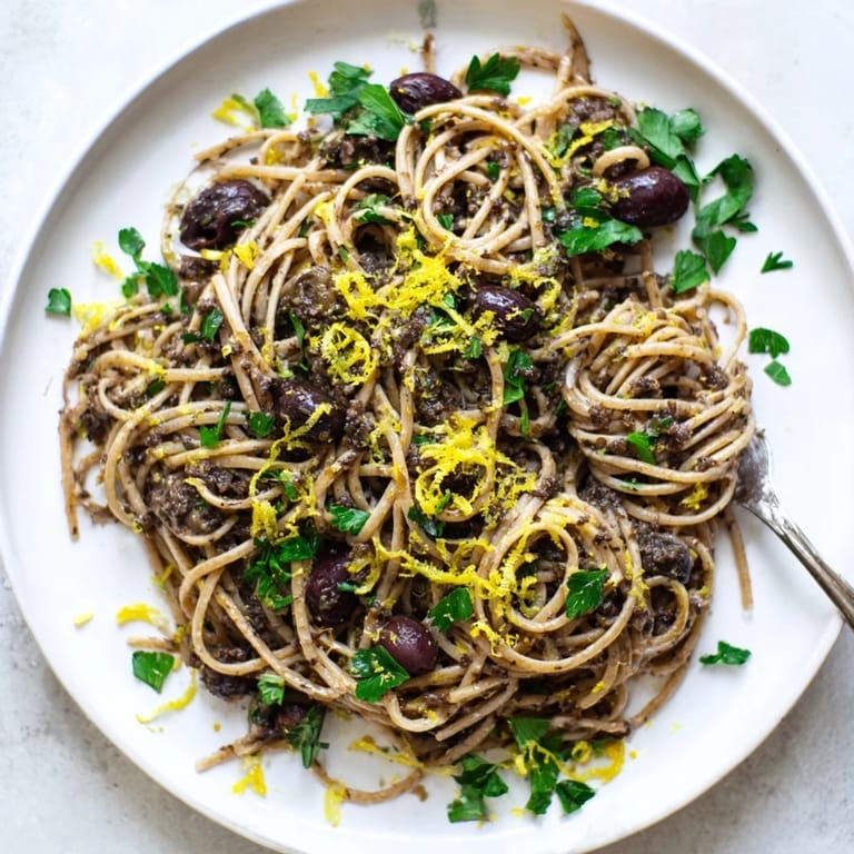 A rustic skillet of Olive Tapenade Pasta, featuring Kalamata olives and capers, served warm with a side salad.