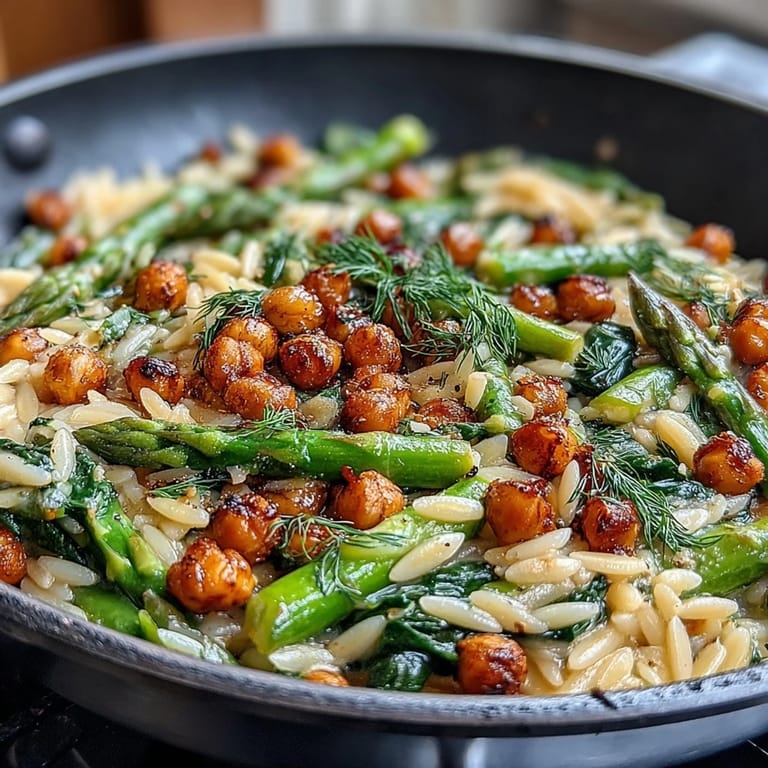 Creamy lemon herb orzo dish packed with chickpeas, asparagus, and fresh spring vegetables for a healthy meal.  